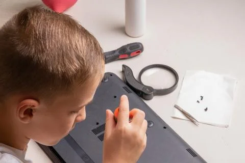 A boy of 10 years old is sorting a laptop for cleaning and maintenance. Selec Stock Photos