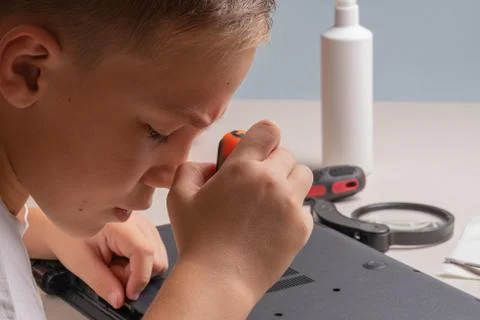 A boy of 10 years old is sorting a laptop for cleaning and maintenance. Selec Stock Photos