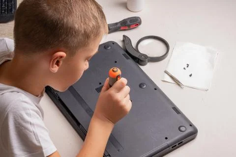 A boy of 10 years old is sorting a laptop for cleaning and maintenance. Selec Stock Photos