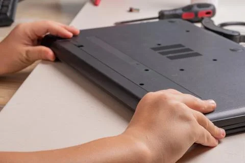 A boy of 10 years old is sorting a laptop for cleaning and maintenance. Selec Stock Photos