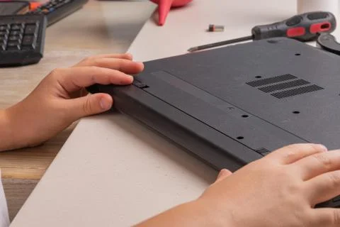 A boy of 10 years old is sorting a laptop for cleaning and maintenance. Selec Stock Photos