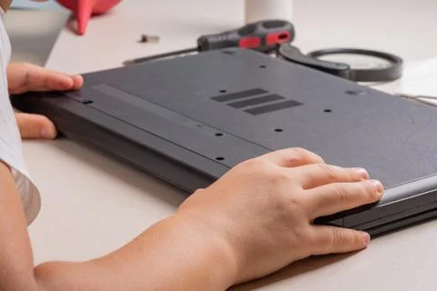 A boy of 10 years old is sorting a laptop for cleaning and maintenance. Selec Foto stock
