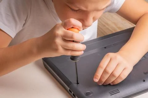 A boy of 10 years old is sorting a laptop for cleaning and maintenance. Selec Stock Photos