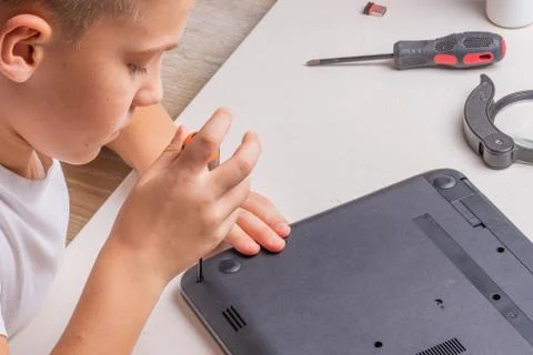 A boy of 10 years old is sorting a laptop for cleaning and maintenance. Selec Stock Photos