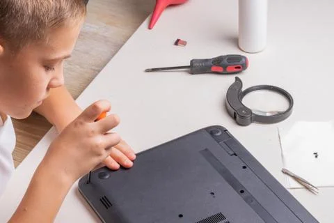 A boy of 10 years old is sorting a laptop for cleaning and maintenance. Selec Stock Photos