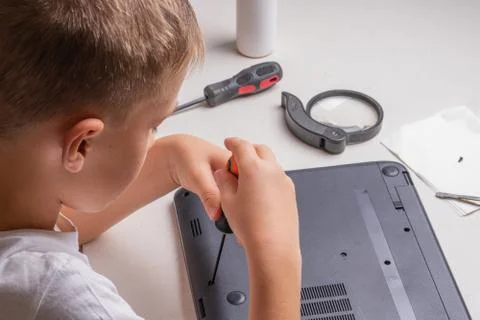A boy of 10 years old is sorting a laptop for cleaning and maintenance. Selec Stock Photos