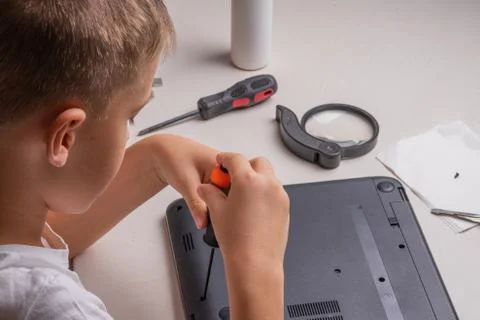 A boy of 10 years old is sorting a laptop for cleaning and maintenance. Selec Stock Photos