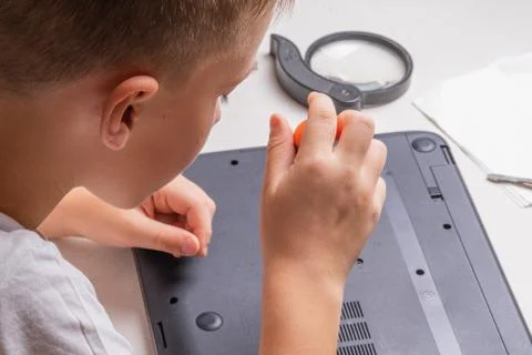 A boy of 10 years old is sorting a laptop for cleaning and maintenance. Selec Foto stock