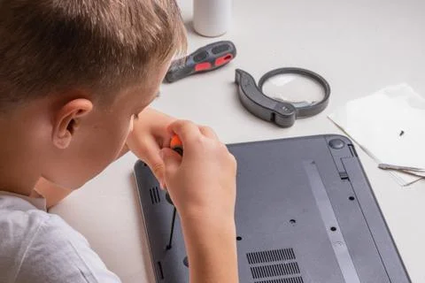 A boy of 10 years old is sorting a laptop for cleaning and maintenance. Selec Stock Photos