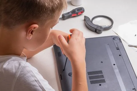 A boy of 10 years old is sorting a laptop for cleaning and maintenance. Selec Stock Photos