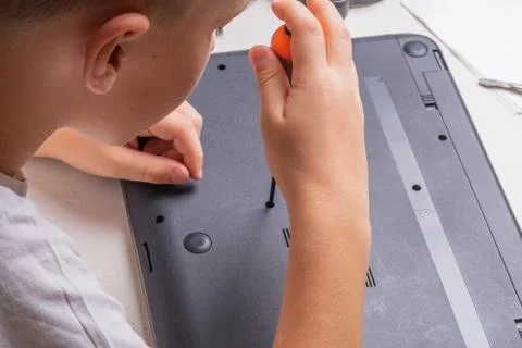 A boy of 10 years old is sorting a laptop for cleaning and maintenance. Selec Stock Photos