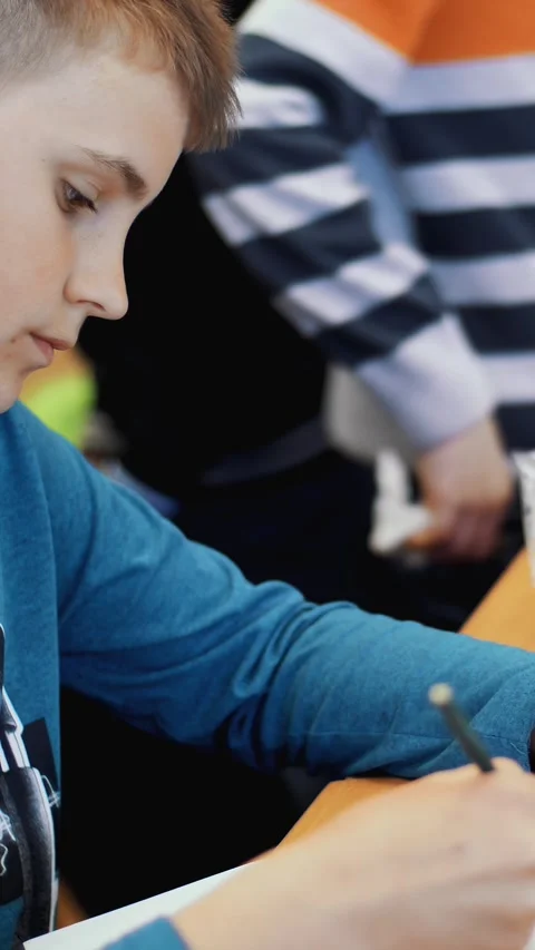The boy of 12 years, draws a drawing, a project of a robot model, a machine, Stock Footage 314657225