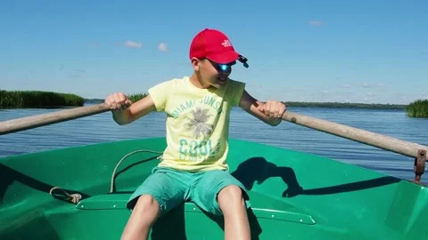 The boy is 12 years old rowing the oars, sailing the boat on the river. Video stock 233578216