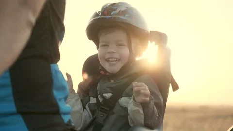 A boy of 2-3 years old in a helmet and in a children's bicycle seat. Dawn Stock Footage 95928583