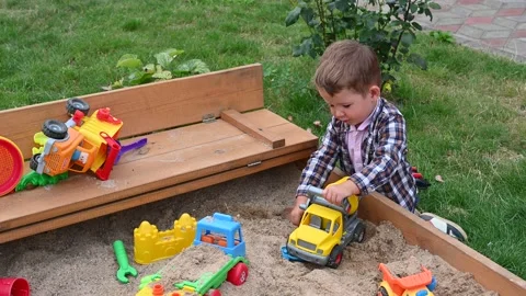 Boy 2-3 years old playing with toy cars in the sandbox. Side view. Stock Footage 151526842