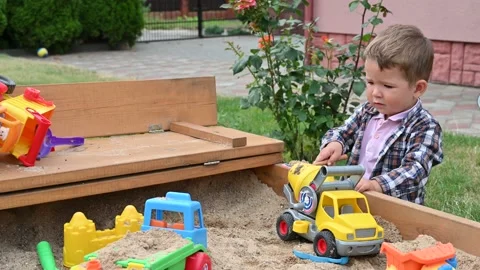 Boy 2-3 years old playing with toy cars in the sandbox. Side view. Stock Footage 151526880