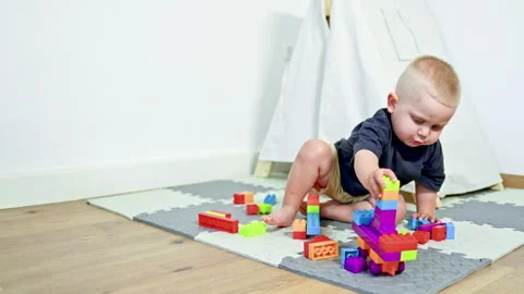 Boy 2 years old at home sits on the floor and builds a constructor. Toddler Video stock 319938458