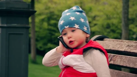Boy 2 years old talking on the phone while sitting in the park. Stock Footage 153559822