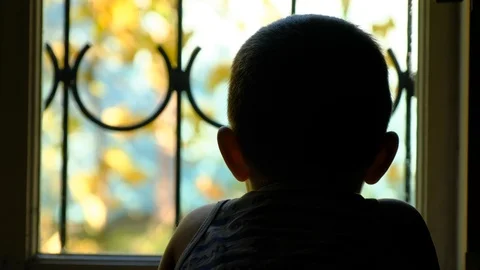 The boy is 3-5 years old outside the window with a lattice Stock Footage 98416823