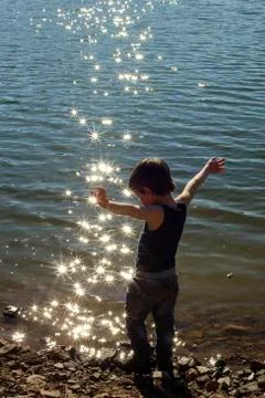 Boy (4-5) standing with outstretched arms on shore Stock Photos