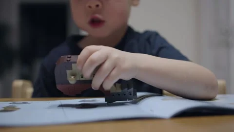 Boy 4-5 years assembles toy according instructions designer without help adults Video stock 242420223