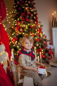 Boy 4-6 years old in a red festive room and a beautiful hairstyle on new year's Stock Photos