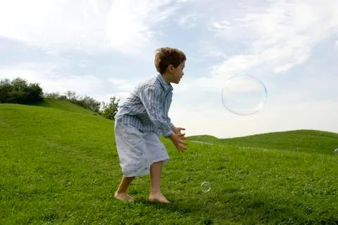 Boy (4-7) playing with soap bubble, side view Stock Photos