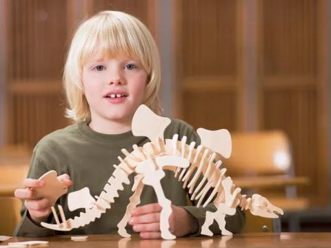 Boy (4-7) sitting with dinosaur skeleton, portrait Stock Photos