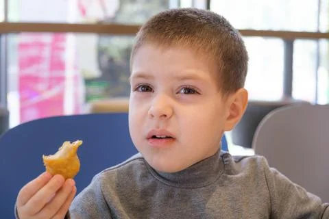 A boy of 4 years old eats nuggets with sauce in a fast food cafe. Stock Photos