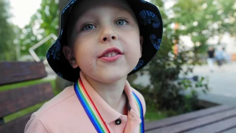 Boy 5 years old in a blue bucket hat shows his tongue on the street Stock Footage 279064438