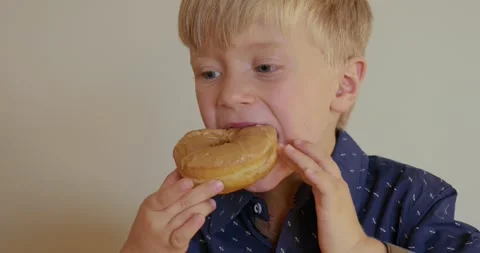 The boy 5 years old eats a sweet caramel donut. 4k Video stock 282838761