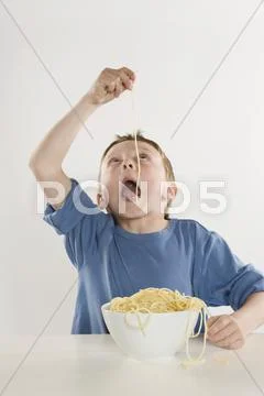 Boy (6-7) eating single spaghetti noodle Stock Photos