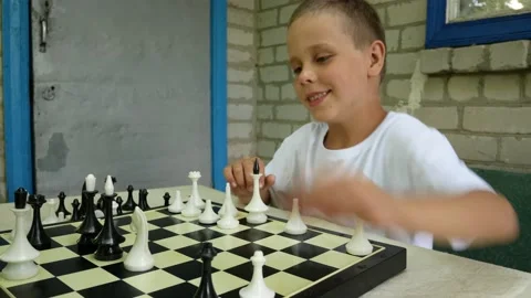 A boy of 6-7 years old plays chess at the dacha at the table Video stock 164324690