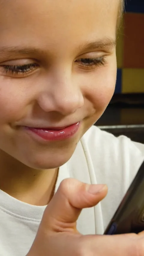 A boy of 6-7 years old holds a phone in his hands, scrolls on the screen, talks Stock Footage 312140921
