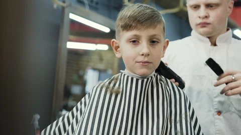 Boy 7-8 years old in barbershop. Happy little boy in beauty salon. Male wizard Stock Footage 87863856