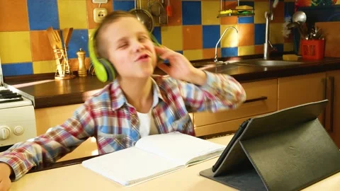A boy of 7-8 years old laughs, waves his hands and sings in headphones in front Stock Footage 229888437