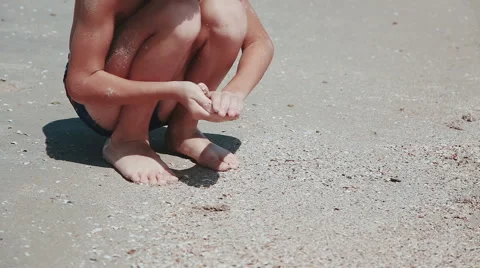 Boy 9 years old sitting on the sand of the sea by the sea. Playing sea sand Stock Footage 66454518