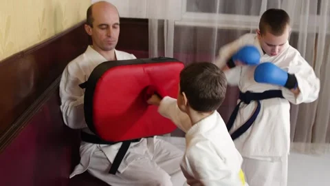 A boy actively punches the simulator in the hands of a trainer Stock Footage 268830330