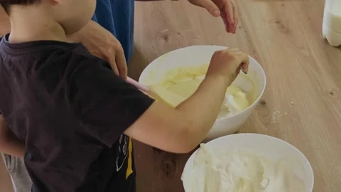 Boy adding with a spoonful of whipped cream, in the cream cheese that my mother Stock Footage 190606683
