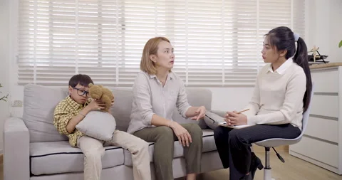 Boy with ADHD hugs stuffed bear during therapy consultation while asian single Stock Footage 319223423