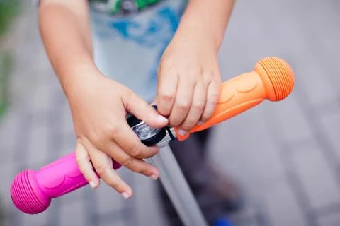 The boy adjusts the flashlight on the steering wheel of a bright scooter Stock Photos