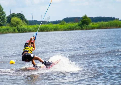 Boy age 9 riding wakeboard on lake Stock Photos