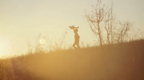 Boy with the airplane in the hands of running on a hill at sunset Stock Footage