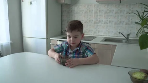 The boy is alone in the kitchen at the table Stock Footage 167590830