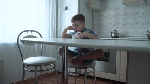The boy is alone in the kitchen at the table Stock Footage 167590845