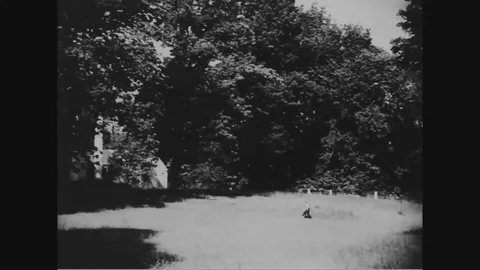 Boy along with his dog running toward church - 1939 Stock Footage 98561873