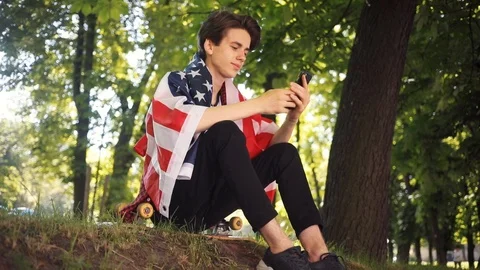 Boy with American flag using mobile phone take selfie smile sitting on skate Video stock 92048440