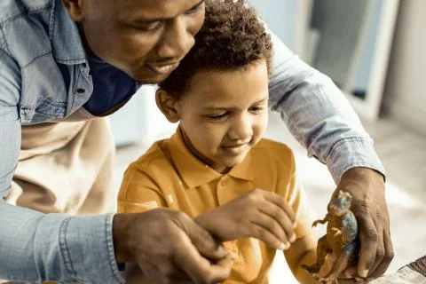 Boy and dad are exploring a plastic dinosaur. Stock Photos