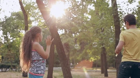 Boy and girl blowing bubbles in the park Stock Footage 71926166