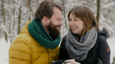 A boy and a girl dressed in warm winter clothes are enjoying each other's Stockbeeldmateriaal 99780341